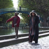 Niño y señora caminando por un parque al lado de un río