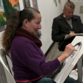 Una dibujante hace un boceto o caricatura de un asistente a las ferias
