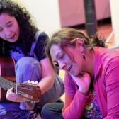 Artista con guitarra y persona sentada al lado escuchando