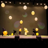 Artistas en tarima jugando con globos y luces de colores