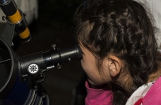 Niña viendo la  luna a través de un telescopio 