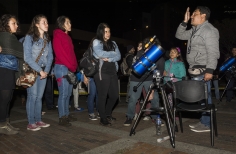 Personas  reunidas al rededor de un telescopio 