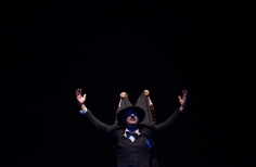 Hombre de negron dos manos que le levantan por detras el extremo del sacoleva