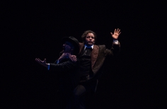 Dos hombres actuando en el escenario oscuro