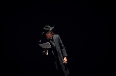 Hombre de negro sosteniendo unos papeles que parece leer