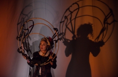 Actriz con circulos proyectando su sombra en la pared del escenario