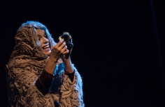 Actriz observando algo que tiene en sus manos y sonriendo