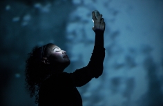 Actriz sosteniendo algo con su mano derecha levantada y sonriendo.