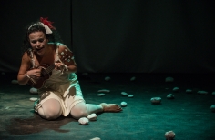 Mujer que llora con instrumento sentada en el piso empedrado del escenario