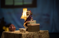 Muñeca con lámpara, cajas y juego de te sobre una mesa