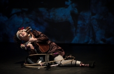 Actriz con guitarra y muñeco inclinada sobre el piso