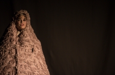 Mujer envuelta en una manta sobre fondo negro