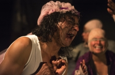 Hombre de cabello largo llorando, con otros actores al fondo.
