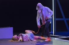 Mujer acostada sobre el piso, mientras un hombre la hala con una cuerda atada a su pie.