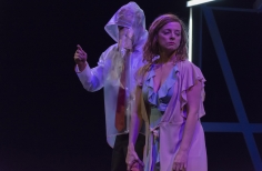 Hombre con impermeable transparente abrazando a mujer con bata.