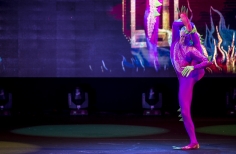 Actor con traje rosa con una pierna detrás de la oreja