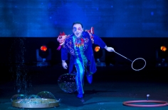 Hombre vestido con disfraz de azules con muñecos sobrepuestos haciendo burbujas.