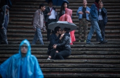 Pareja besandose bajo una sombrilla, bajo la lluvia en las graderias de la Media Torta