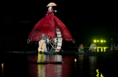 Marioneta gigante sobre rueda y actores en el lago.