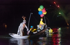 Actores soibre bicicleta con globos y góndola sobre el lago.