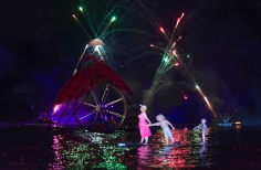 Rueda gigante y mujer con niño - marioneta sobre el lago iluminado.