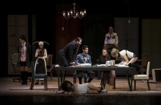 Actores en escena alrededor de una mesa