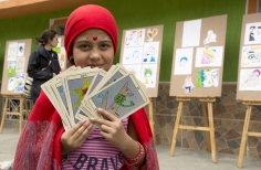 Niña disfrazada de lectora del tarot, vestida de rojo con cartas grandes.