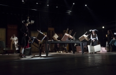 Escenario con mesas, sillas y actores