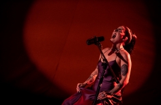 Cantante Delfina Dib cantando en fondo rojo. 