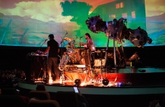 Agrupación musical tocando en vivo en tarima del domo del Planetario de Bogotá con proyección audiovisual. 