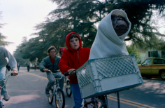 Dos jóvenes en bicicleta con un extraterrestre en la canastilla