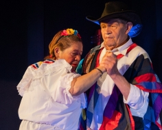 dos personas mayores bailan en un escenario