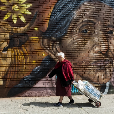 Adulto mayor caminando frente  a un grafiti