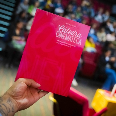 Mano sosteniendo el libro de  Memorias Cátedra Cinemateca: éticas, estéticas y políticas del cine colombiano