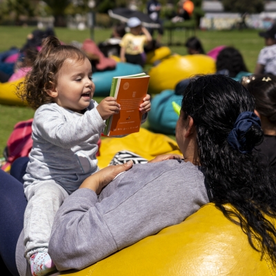 Niña jugando con su mamá y con un libro