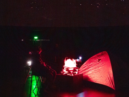 Foto de un hombre viendo las estrellas al lado de una carpa en el Planetario