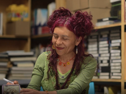 captura de pantalla del video de entrevista de la Escritora Liliana Moreno, quien se encuentra en una biblioteca escribiendo