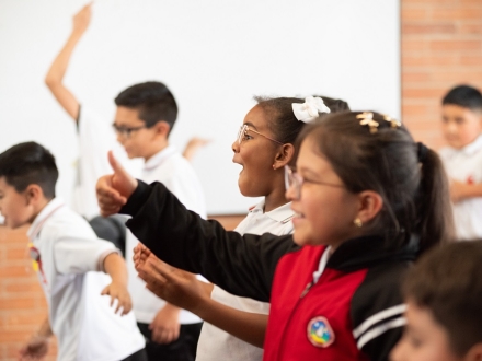 Cinco niños en fila sonrien mientras hacen un gesto de aprobación con las manos