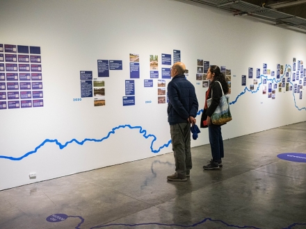 Un hombre y una mujer repasan la línea del tiempo colocada en la exposición de Ciudad de Agua