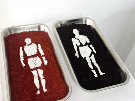 dos contenedores con polvo de color rojo y negro y una figura humana en blanco en cada uno 