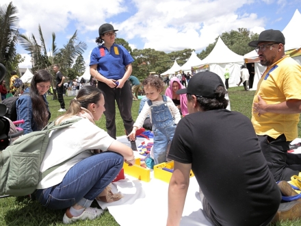una niña juega con unos bloques de madrea mientras tres adultos la miran