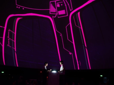 En el domo del planetario dos personas manipulan un dispositivo que les permite cambiar en tiempo real las imagenes y sonidos que se proyectan