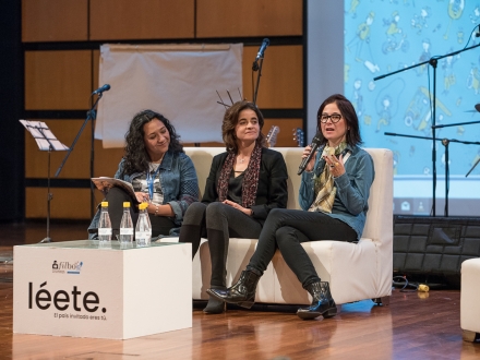 Mujeres conversan en auditorio