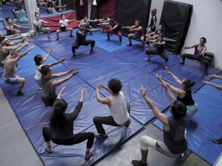 Acróbatas en actividad práctica, agachados haciendo ejercicios del taller.