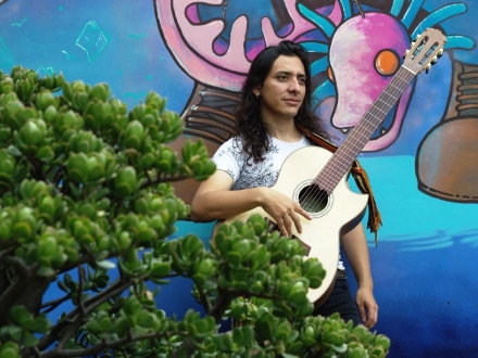 Hombre con guitarra entre arbustos 