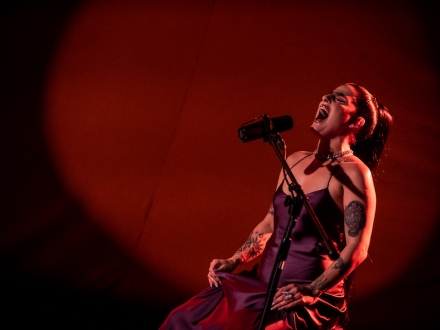 Cantante Delfina Dib cantando en fondo rojo. 