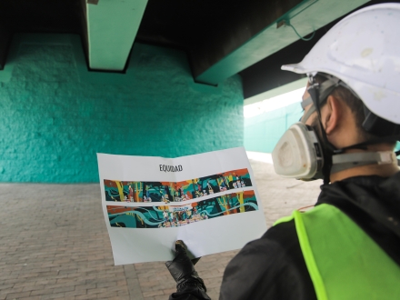 Hombre ve un diseño de papel para plasmarlo en el puente de la 170, en el marco del Museo Abierto de Bogotá. Foto: Kadir Molano / Idartes.