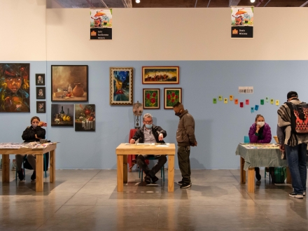 Foto de expositores en las Ferias Locales de Artes de la Candelaria sentados en mesas con sus creaciones