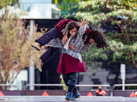 Mujer carga a hombre en una obra de teatro. 
