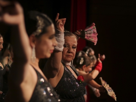 Mujer adulta mayor bailando en escenario. 